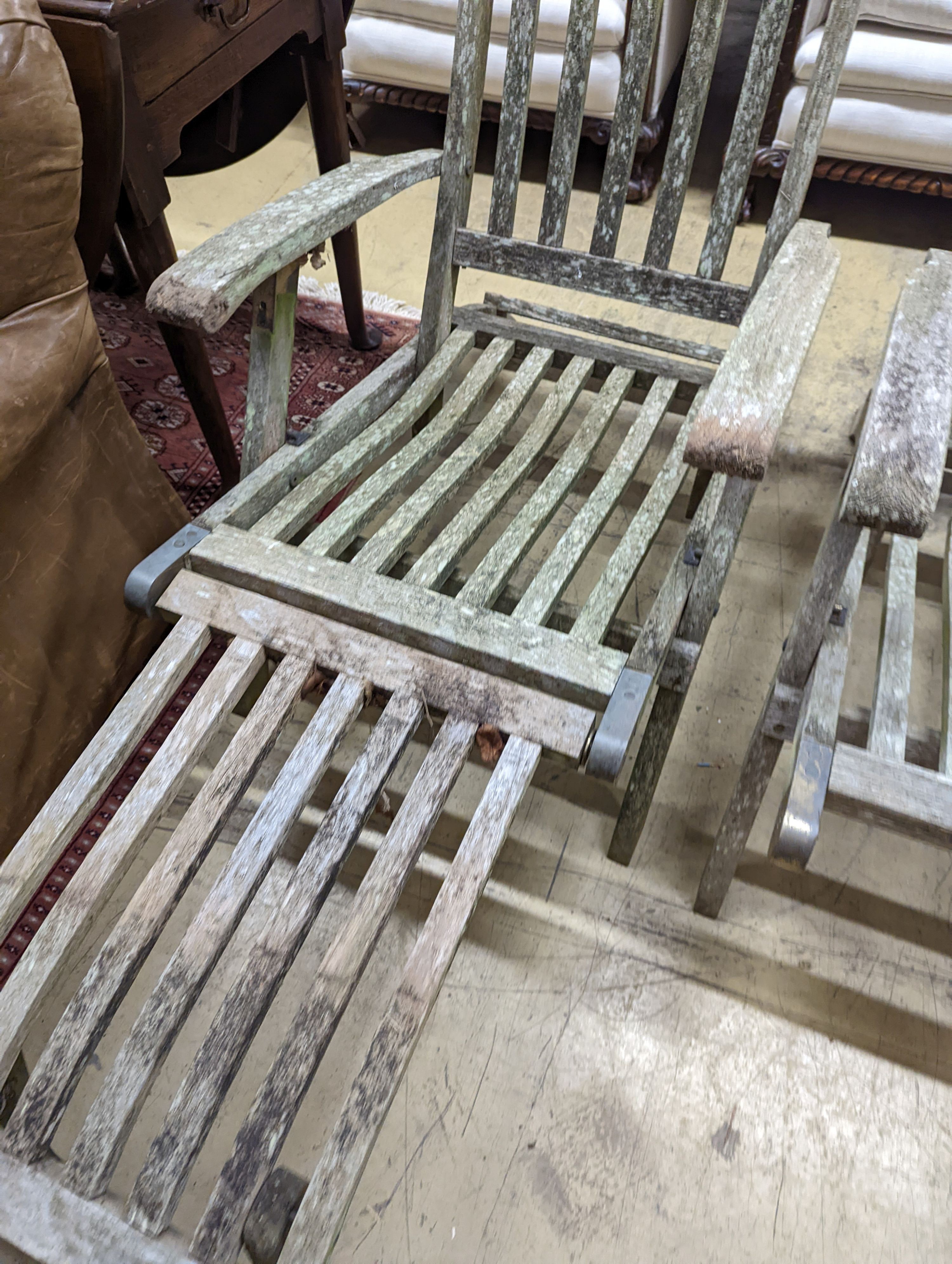 A pair of weathered teak garden steamer chairs, one lacks foot piece. H-93cm.
